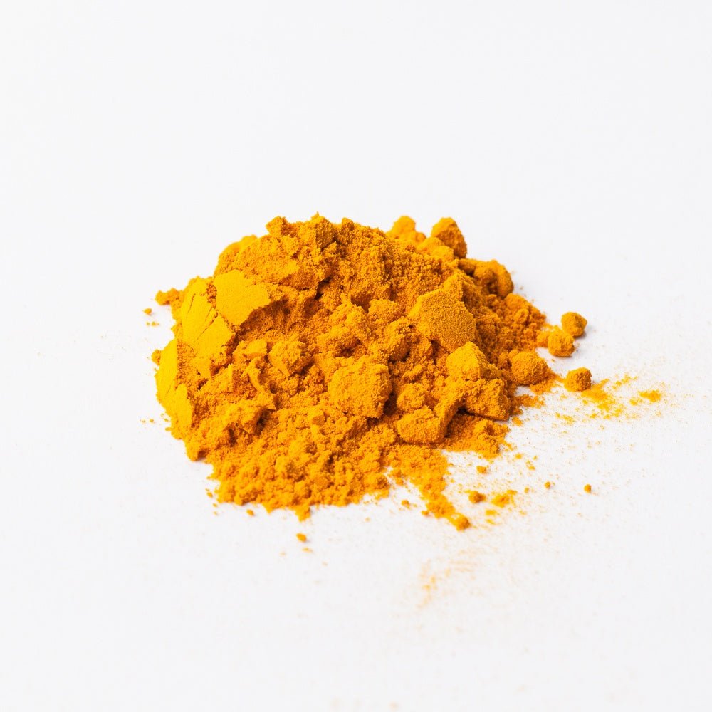 Small pile of organic ground turmeric root on a white background