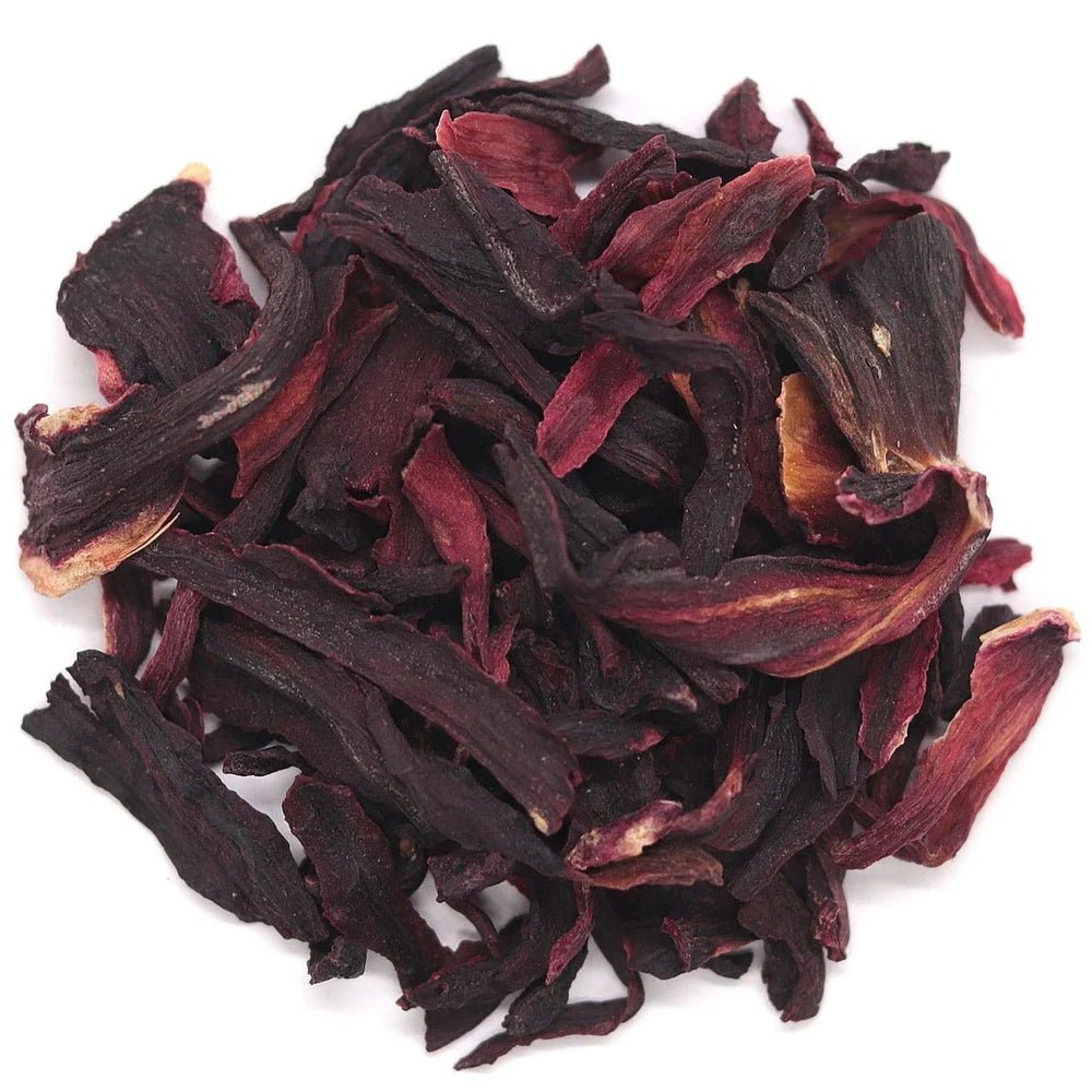 Pile of organic dried hibiscus flowers, deep crimson, on a white background
