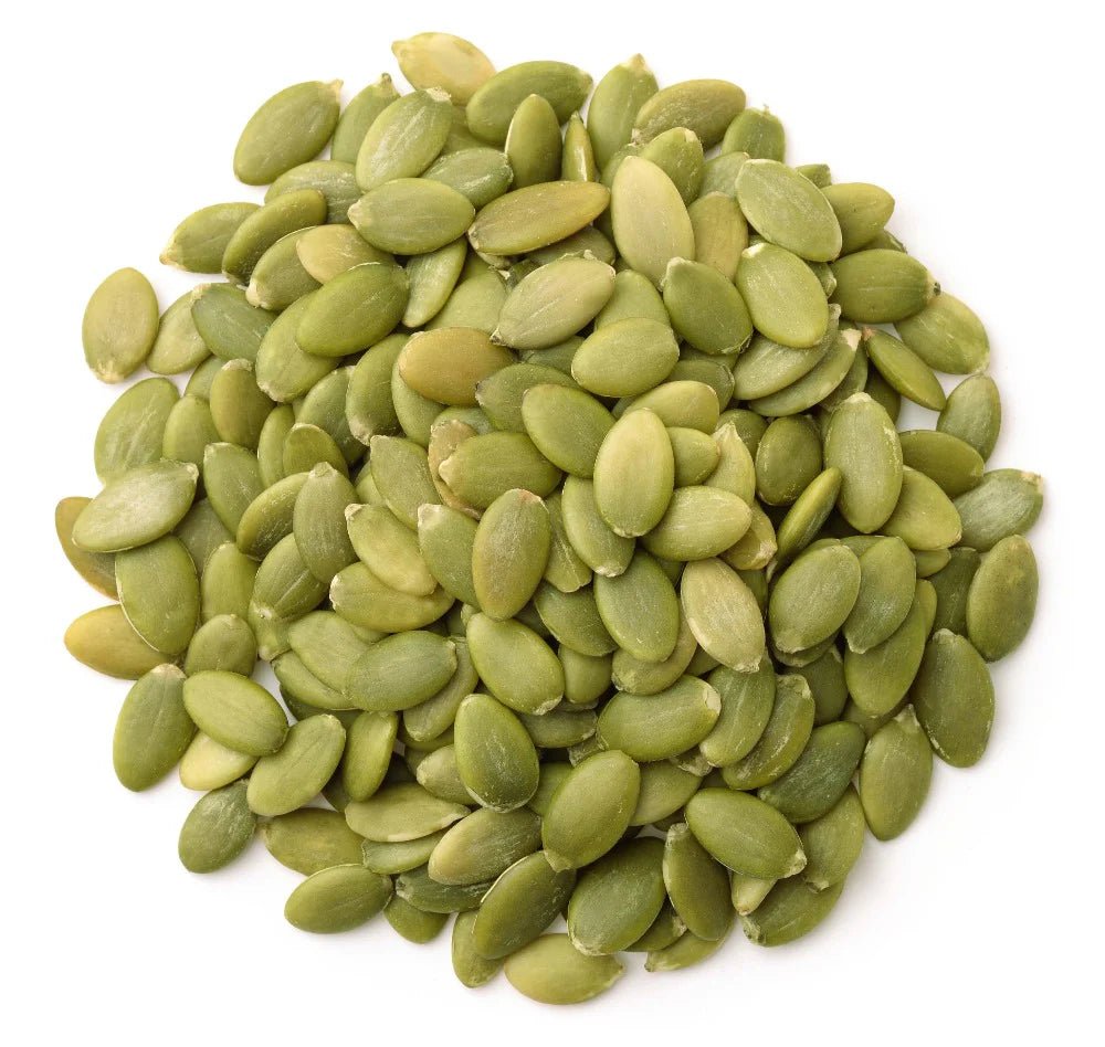 Pile of organic green pumpkin seeds (pepitas) on a white background