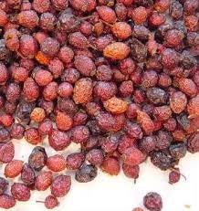 Pile of organic whole dried rose hips on a white background