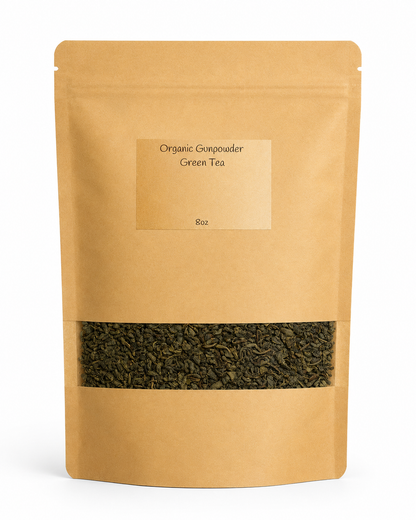 Kraft paper tea bag with organic gunpowder green tea leaves on a white background