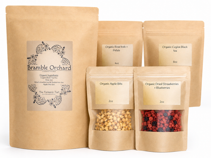A set of brown bags that are resealable at the top with cream labels, from left to right we see the largest bag with the name of the bundle of tea Bramble orchard, from there we see smaller bags to the right organic apple bits are in the front along with a mix of blueberries.
the rose buds and petals and ceylon black tea are in the back from left to right respectively 